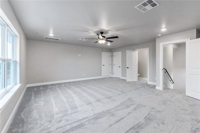 unfurnished bedroom with multiple windows, light carpet, and ceiling fan