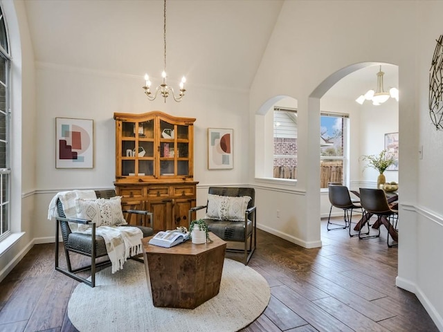 living area with high vaulted ceiling, dark wood-type flooring, and a notable chandelier