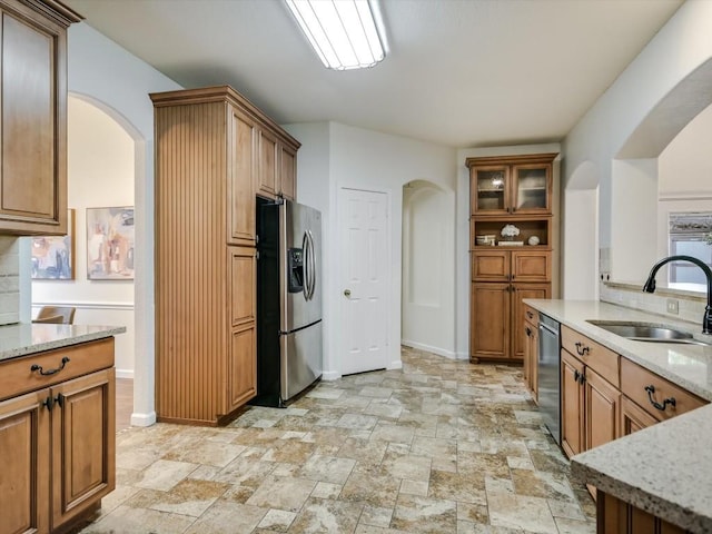 kitchen with light stone countertops, stainless steel appliances, and sink