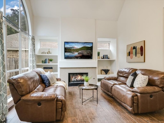 living room with hardwood / wood-style flooring, built in shelves, and vaulted ceiling