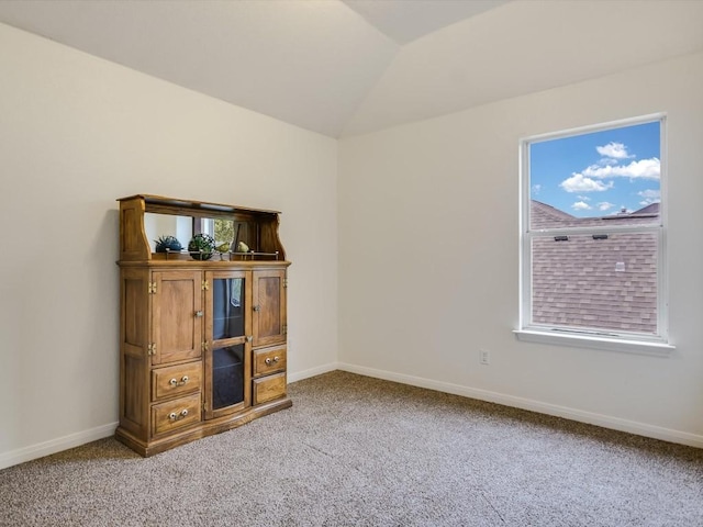 carpeted spare room featuring lofted ceiling