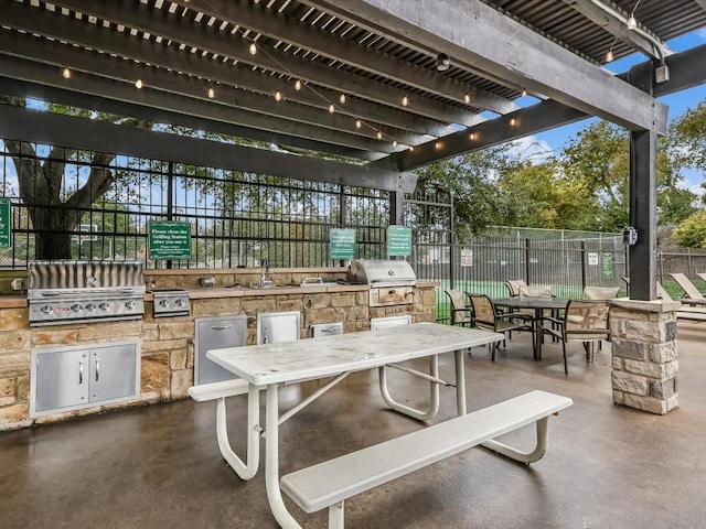 view of patio with area for grilling, a pergola, and sink