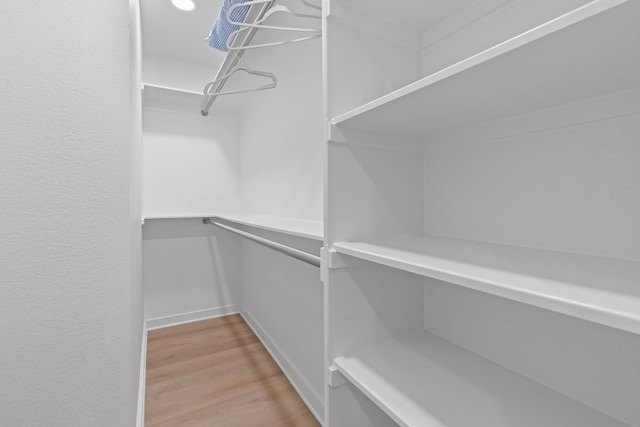 walk in closet with light hardwood / wood-style floors