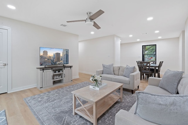 living room featuring light hardwood / wood-style flooring and ceiling fan