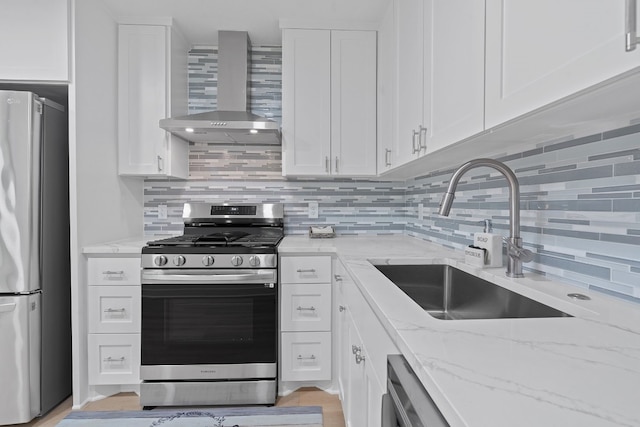 kitchen featuring white cabinetry, sink, stainless steel appliances, wall chimney range hood, and backsplash