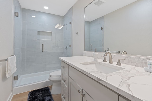 bathroom with hardwood / wood-style flooring, vanity, toilet, and an enclosed shower