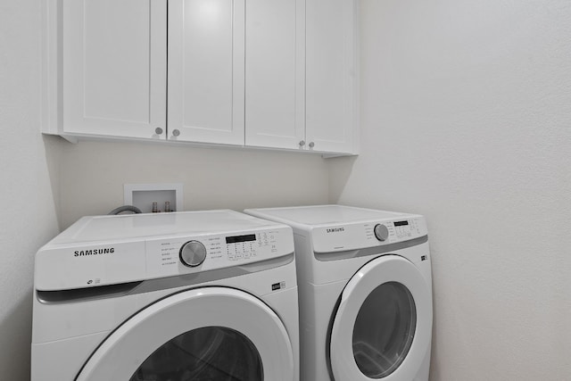 clothes washing area featuring cabinets and separate washer and dryer