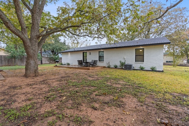 rear view of house featuring central AC unit and a lawn