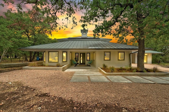 back house at dusk featuring covered porch