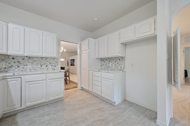 kitchen featuring decorative backsplash, white cabinetry, and a chandelier