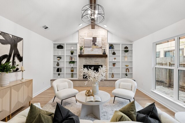 living room with vaulted ceiling, an inviting chandelier, a fireplace, and light hardwood / wood-style flooring