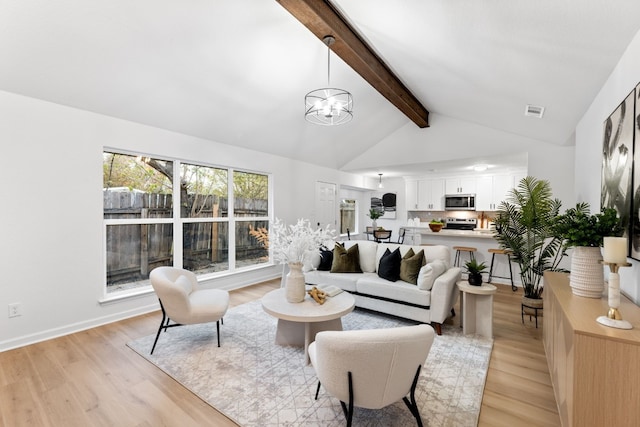 living room with an inviting chandelier, light hardwood / wood-style floors, and lofted ceiling with beams