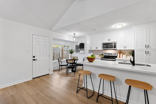 kitchen with appliances with stainless steel finishes, sink, a breakfast bar area, and white cabinets