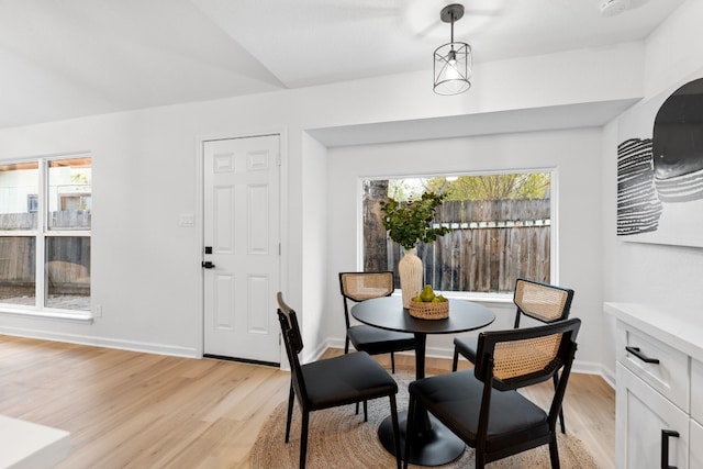 dining room with light hardwood / wood-style flooring, a healthy amount of sunlight, and vaulted ceiling