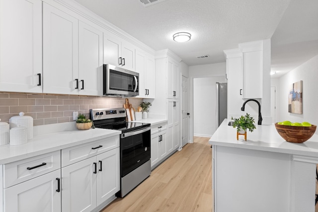 kitchen featuring sink, white cabinetry, light hardwood / wood-style flooring, appliances with stainless steel finishes, and decorative backsplash