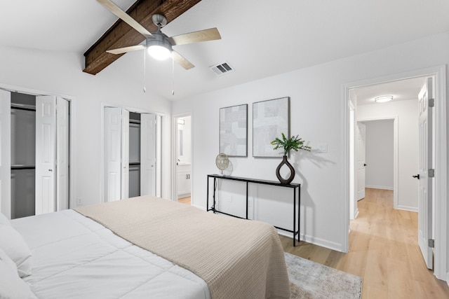 bedroom with connected bathroom, lofted ceiling with beams, ceiling fan, multiple closets, and light hardwood / wood-style flooring