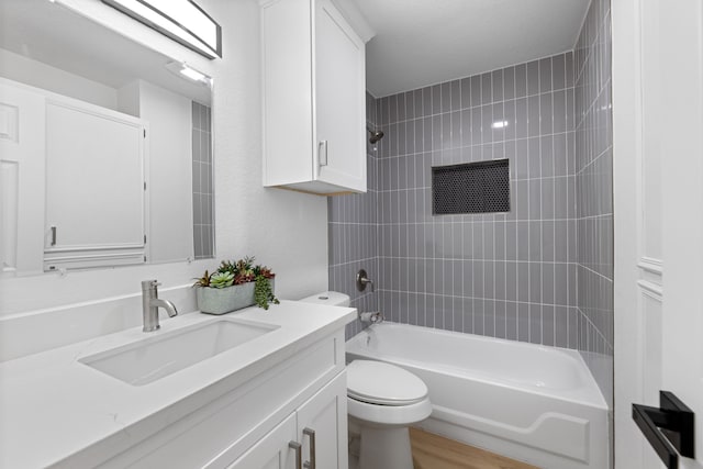 full bathroom with tiled shower / bath combo, vanity, hardwood / wood-style flooring, and toilet