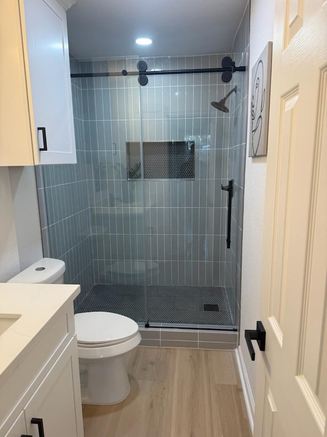 bathroom featuring walk in shower, vanity, toilet, and hardwood / wood-style floors