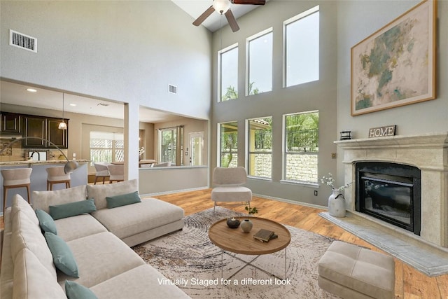 living room with a high ceiling, ceiling fan, and wood-type flooring