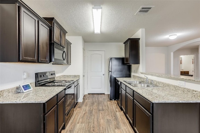 kitchen with black appliances, sink, light wood-type flooring, a textured ceiling, and kitchen peninsula