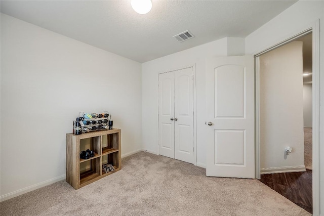 bedroom featuring a closet, light colored carpet, and a textured ceiling