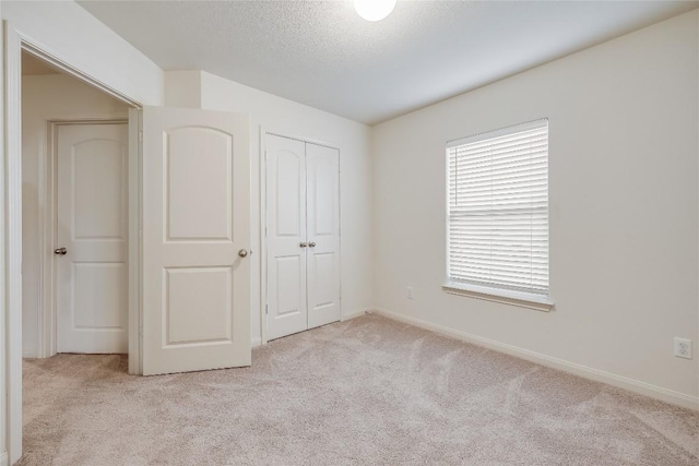 unfurnished bedroom with a textured ceiling, light carpet, and a closet