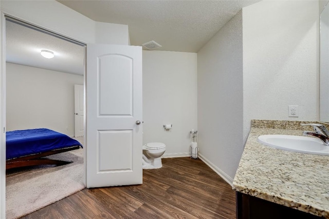 bathroom featuring vanity, wood-type flooring, a textured ceiling, and toilet