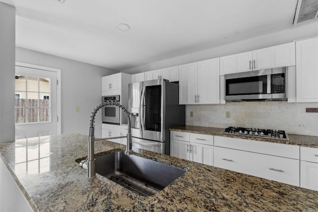 kitchen with stone countertops, white cabinetry, and appliances with stainless steel finishes