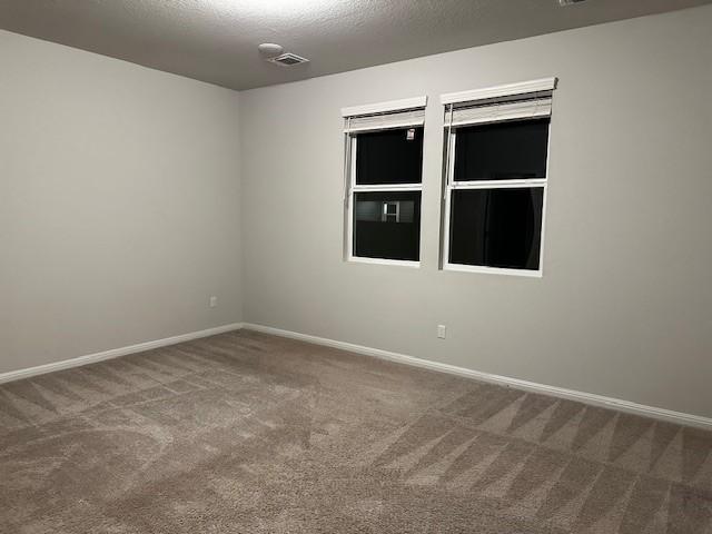 spare room featuring carpet flooring and a textured ceiling