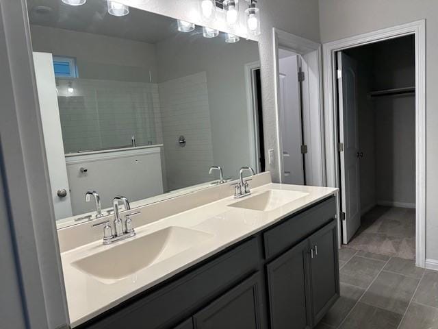 bathroom featuring tile patterned flooring, vanity, and a tile shower