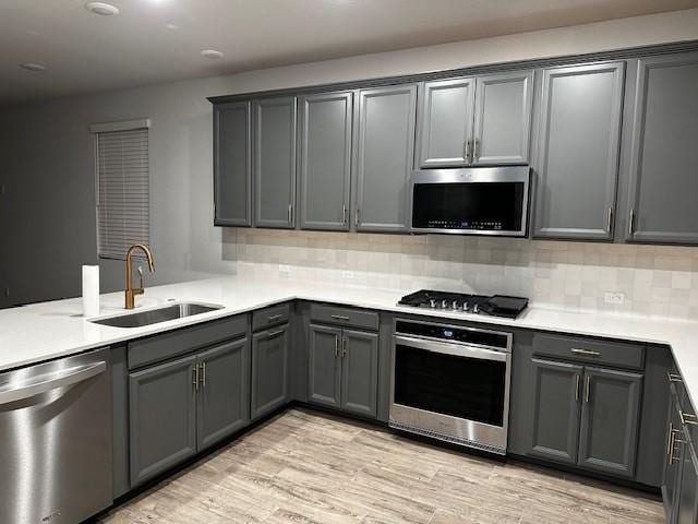 kitchen featuring stainless steel appliances, gray cabinets, tasteful backsplash, and sink