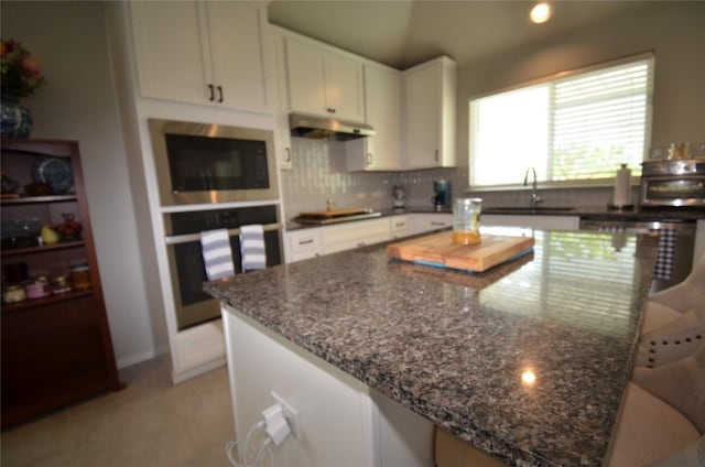 kitchen with sink, decorative backsplash, dark stone countertops, appliances with stainless steel finishes, and white cabinetry