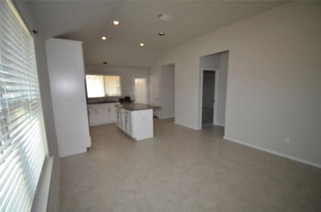 unfurnished living room with recessed lighting, baseboards, and vaulted ceiling