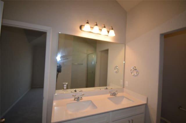 bathroom featuring double vanity, walk in shower, and a sink