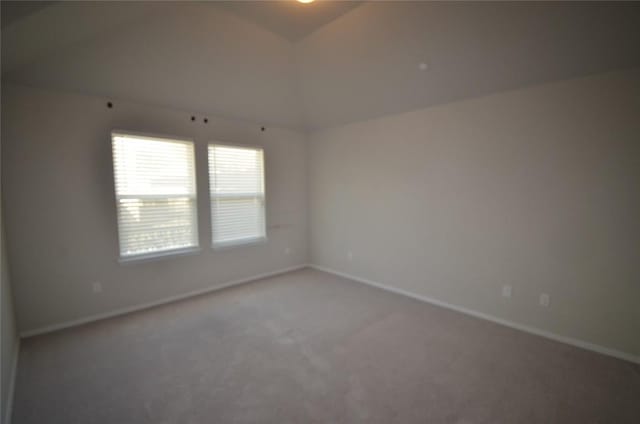 empty room with baseboards, lofted ceiling, and carpet flooring