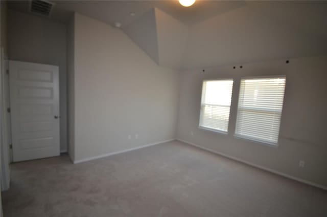 carpeted empty room with visible vents, baseboards, and lofted ceiling