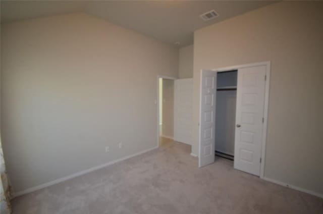 unfurnished bedroom with visible vents, lofted ceiling, a closet, baseboards, and light colored carpet