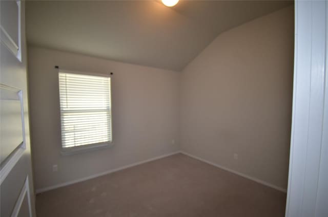 carpeted empty room with vaulted ceiling and baseboards