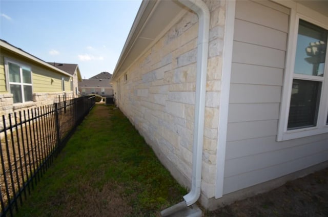 view of property exterior featuring stone siding and fence