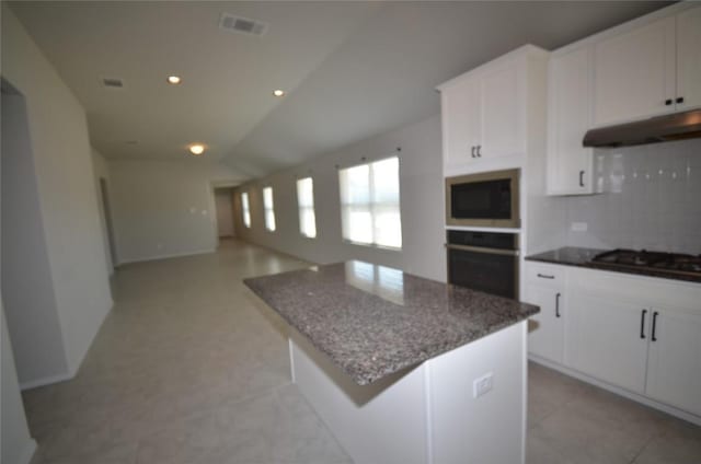 kitchen with oven, black gas cooktop, under cabinet range hood, backsplash, and a center island