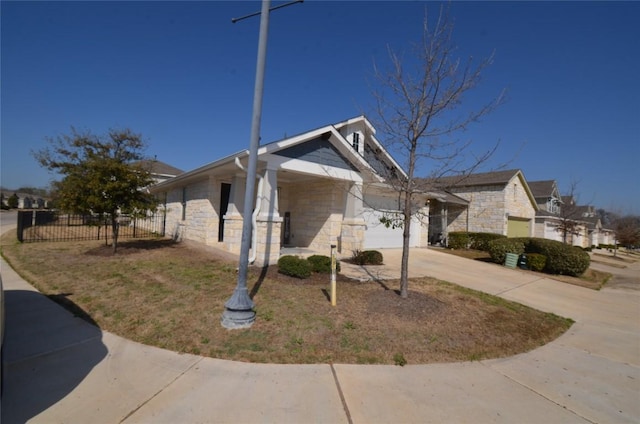 view of home's exterior featuring stone siding, concrete driveway, a garage, and fence