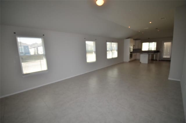 unfurnished living room featuring lofted ceiling and baseboards