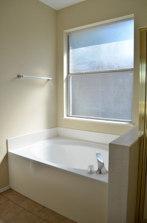 bathroom with a washtub, tile patterned flooring, and a wealth of natural light