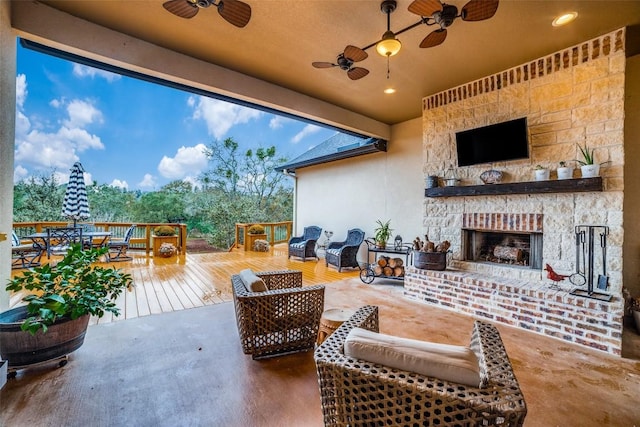 view of patio with a wooden deck, ceiling fan, and an outdoor living space with a fireplace