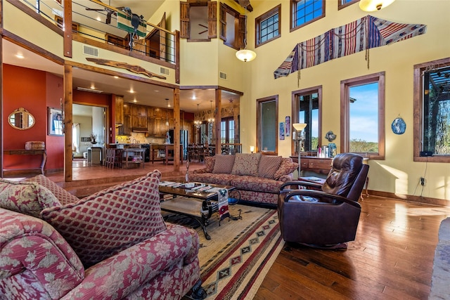 living room featuring a high ceiling, wood-type flooring, and an inviting chandelier