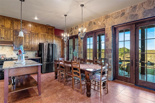 dining room with a notable chandelier, french doors, and dark tile patterned flooring