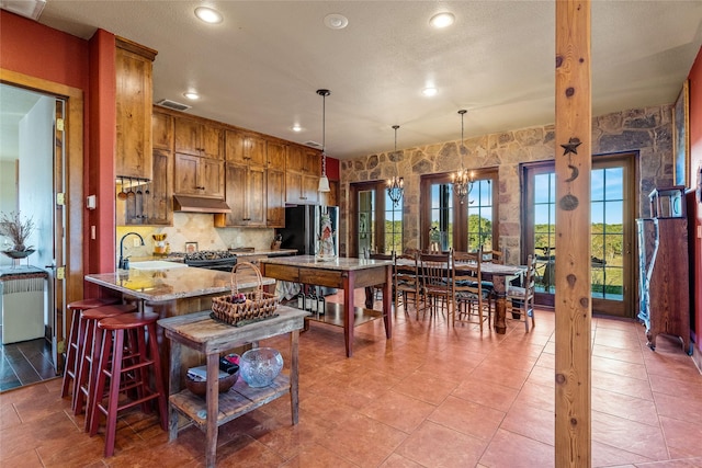 kitchen featuring hanging light fixtures, a kitchen breakfast bar, light stone countertops, french doors, and kitchen peninsula