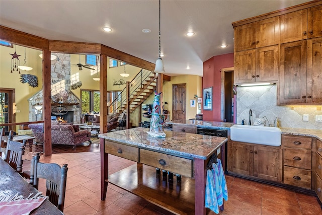 kitchen with light stone counters, backsplash, a fireplace, and sink