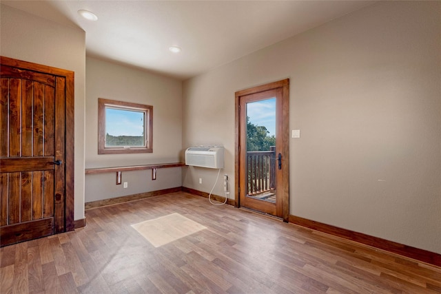 empty room featuring a wall mounted AC and light hardwood / wood-style flooring