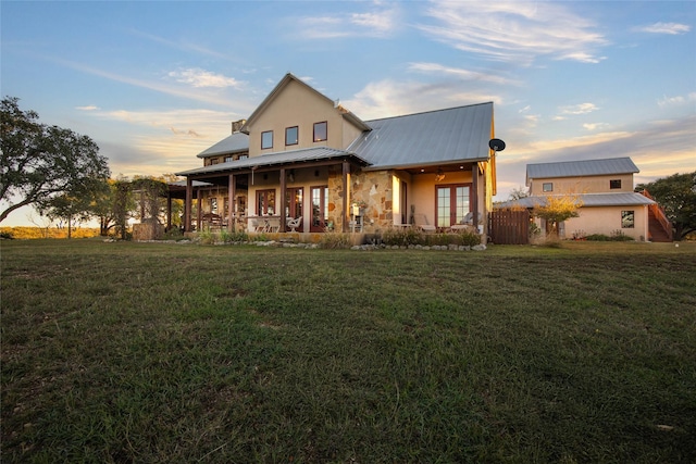 back house at dusk with a yard and french doors